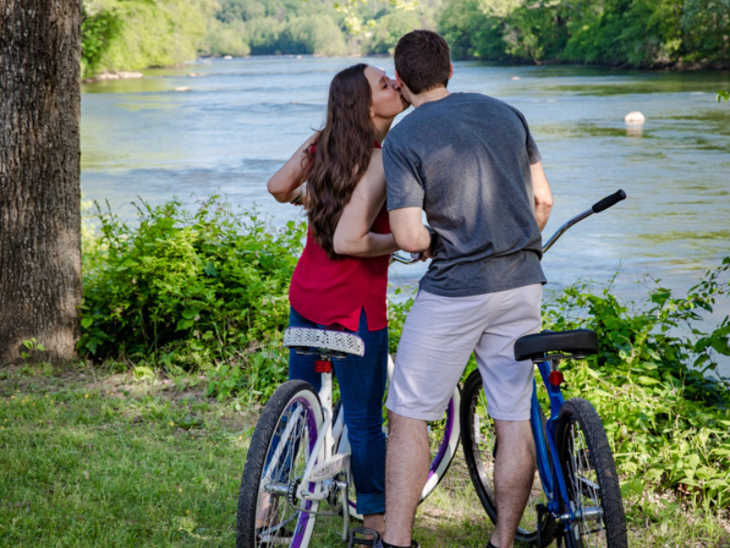 couple kissing while riding bikes by the river