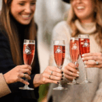 4 women in winter attire stand together, clinking their wine glasses at Potomac Point Winery